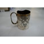 A small silver mug decorated with floriated design with a central cartouche engraved. Silver gilt in