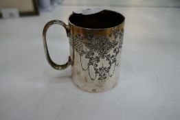 A small silver mug decorated with floriated design with a central cartouche engraved. Silver gilt in