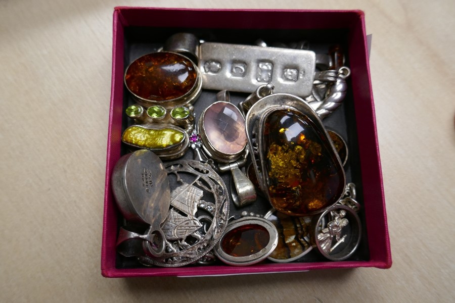 A small collection of various silver pendants, to include several Amber examples, a pink gemstone, b