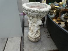 A small stone effect bird bath depicting three children