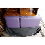 A heavy wooden framed massage bed with purple cushion top, in a black zip up bag