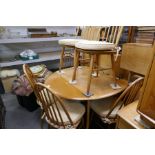 An Ercol style 2 flap kitchen table on splay legs and a set of 6 stick back dining chairs