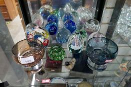 A shelf of glass paperweights and two coloured bowls