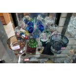 A shelf of glass paperweights and two coloured bowls