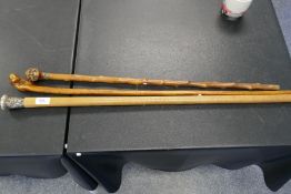 An old walking stick having carved head knob, a Chinese silver cane and one other