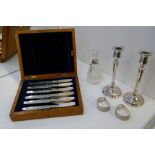 A pair of silver candlesticks, a pair of silver engine turned napkin rings, a cut glass bottle with