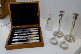 A pair of silver candlesticks, a pair of silver engine turned napkin rings, a cut glass bottle with