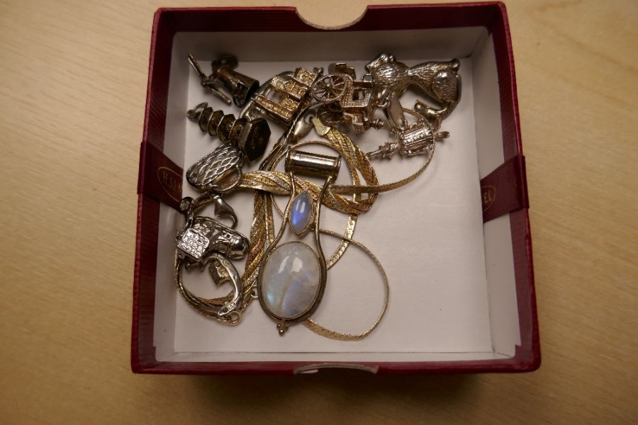 A collection of silver charms, to include a WANG HING example, a silver moonstone pendant, etc