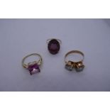 Three 9ct yellow gold dress rings, one set with pale pink gemstone and diamond chips, another purple