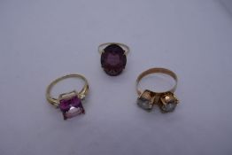 Three 9ct yellow gold dress rings, one set with pale pink gemstone and diamond chips, another purple