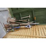 A bundle of long handled wooden garden tools, etc