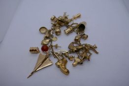 9ct yellow gold charm bracelet hung with approx 31 charms to include Clam, aeroplane, shell, Aladdin