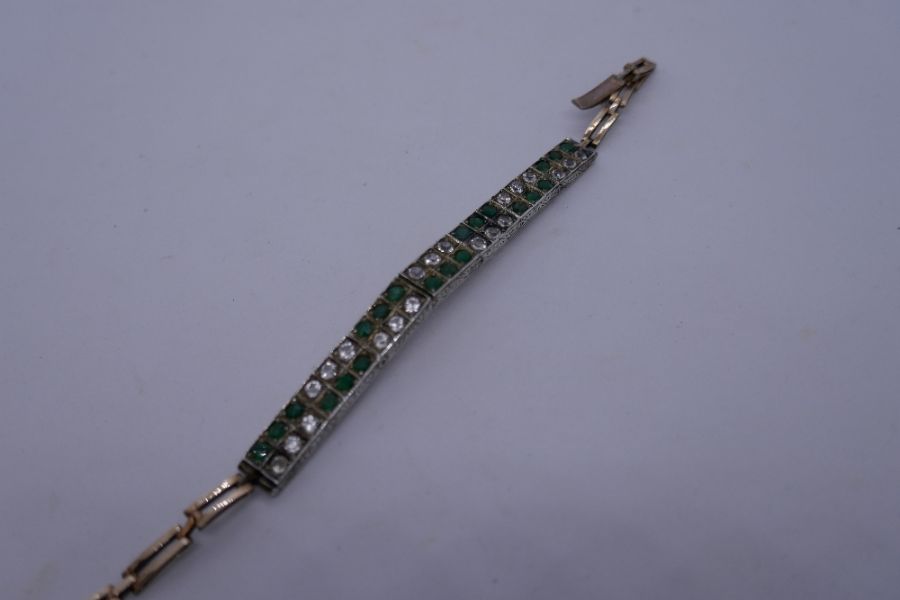 Antique two tone bracelet with articulated white panels set emeralds and possibly white sapphires on