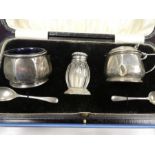 A silver cruet set cased, consisting of salts, a silver topped pepper and two spoons. Along with sil