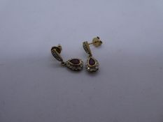 Pair of 9ct yellow gold drop earrings set with central pear shaped ruby surrounded diamonds, marked