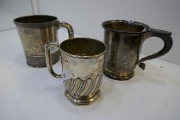 Three silver cups, one decorated with engraved and embossed design and a central cartouche, Sterling