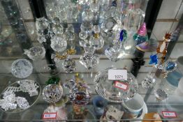 A shelf of glass animals, trinkets, glass clock, paperweights, some being Swarovski