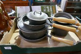 A box of cast iron saucepans and sundry, including a heavy metal cooking grid