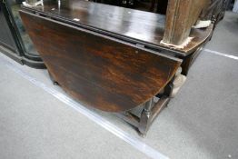 An antique oak oval gateleg table, having one drawer on turned supports, 134cm