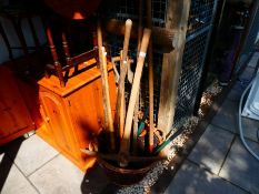 Wicker basket containing long wooden handled garden tools