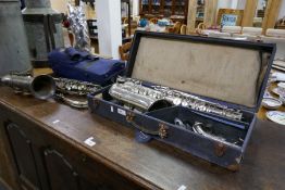 An old silver plated saxophone by René Guenot, one other similar saxophone by Guenot, and a trumpet