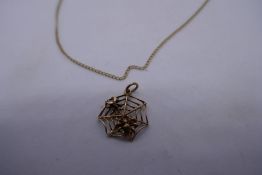 9ct yellow gold necklace hung with a spider web pendant and a 9ct yellow gold cobweb charm, also mar