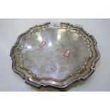 An Edwardian silver tray of circular form with Chippendale pie crust rim on three feet. With a centr