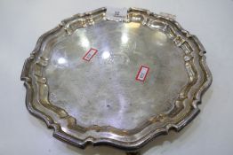 An Edwardian silver tray of circular form with Chippendale pie crust rim on three feet. With a centr