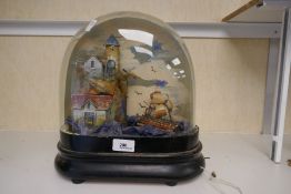 An old musical and moving diorama of masted ship beside buildings and cliff, in glass dome