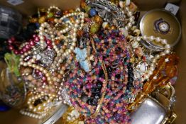 A tray of mixed costume jewellery to include amber coloured necklaces, compacts, etc