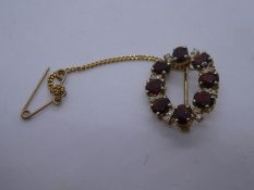 9ct yellow oval brooch with safety chain inset with garnet and diamond chips, marked 375, 2.5cm appr