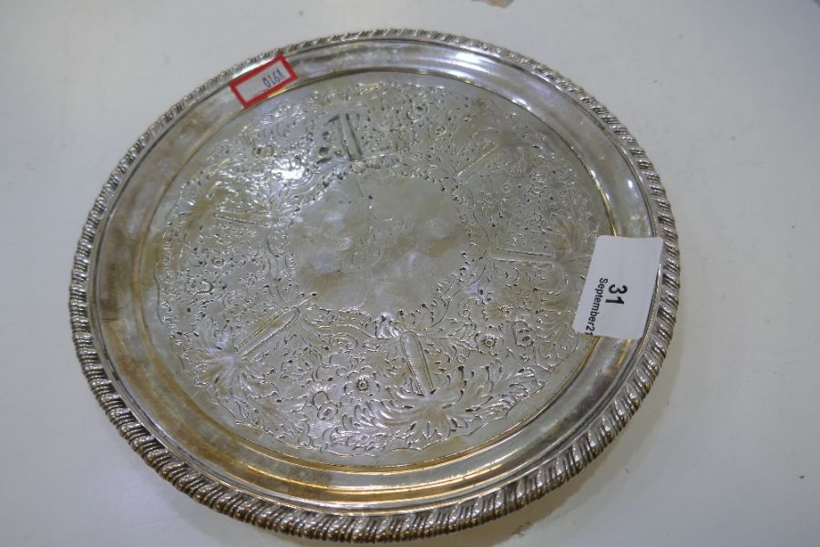 A very heavy circular Georgian silver tray of decorative foliate design, on three feet, with gadroon