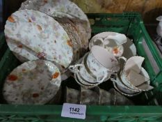 A small green crate of floral tea ware to include tea plates, cups, saucers, jug, bowl etc