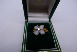 Pretty 9ct dress ring set with 4 oval white opals, and central diamond floral decoration gold should