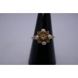 9ct yellow gold dress ring in the form of a flower with central diamond surrounded seed pearls and d