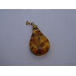 Yellow metal pendant hung with pear shaped amber stone