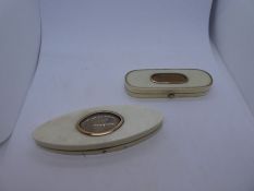 Two antique compact mirrors on oval extension, both with yellow applied metal decoration both mirror