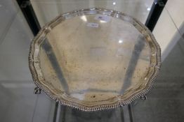 A large silver tray of circular form on four claw feet, with gadrooned borders. Hallmarked Sheffield