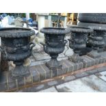 Set of four Victorian style cast iron two handled urns with face decoration on square bases