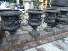 Set of four Victorian style cast iron two handled urns with face decoration on square bases