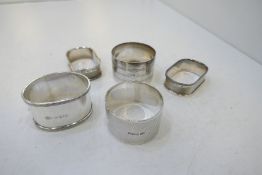 A selection of five silver napkin rings, one matching pair. With various hallmarks and designs inclu