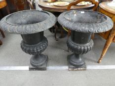 A pair of Victorian black painted cast iron urns on square base, height 77cms