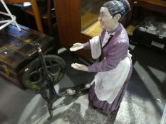 A model of an elderly lady and an iron spinning wheel
