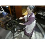 A model of an elderly lady and an iron spinning wheel