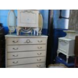 A cream painted chest having five long drawers, a triple mirror and matching beside table