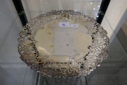 A decorative, hand pierced silver cake stand with a grapevine border. On a raised pedestal base. Hal