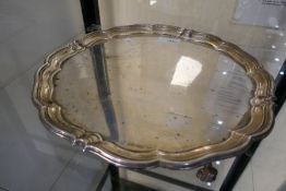 A large circular silver tray on four feet, with engraved message underneath hallmarked Sheffield 191