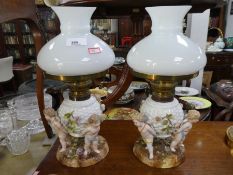 A pair of Sitzendorf porcelain oil lamps, each decorated with 3 cherubs 33.5cm
