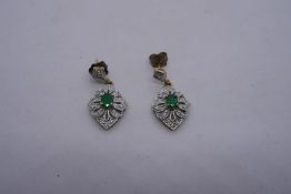 A pair of 9ct yellow deco style emerald and diamond drop earrings with central oval emeralds, approx