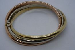 9ct tri colour gold bangle of stepped twist design, 6cm diameter, marked 375, with clasp either side